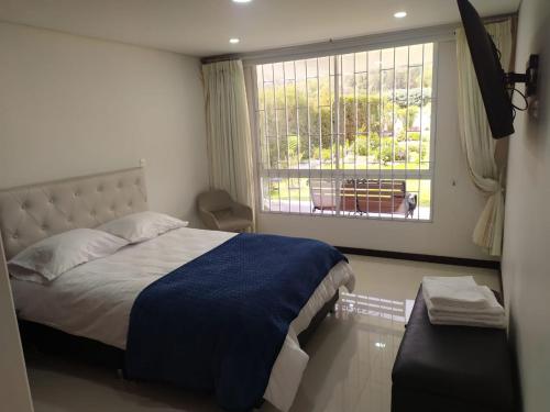 een slaapkamer met een groot bed en een raam bij Estadia independiente en el campo Boyacense in Duitama
