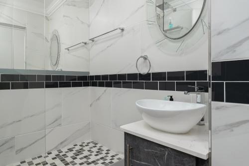 bagno bianco con lavandino e specchio di Modern 1 Bedroom in Blouberg a Città del Capo