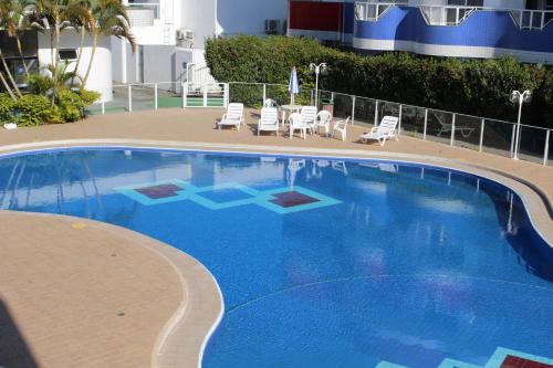 uma grande piscina azul com cadeiras e um edifício em Holiday Ingleses em Florianópolis