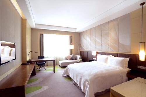 a bedroom with a bed and a desk and a television at Hai Tian Expo Hotel in Qingdao