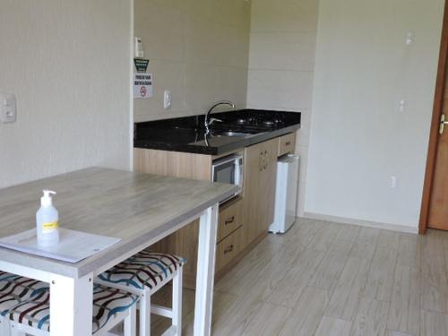 a kitchen with a counter and a sink and a table at Pousada Villa Romantica in Nova Petrópolis