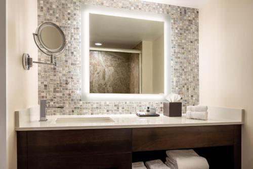 a bathroom with a mirror, sink, and bathtub at Opal Grand Oceanfront Resort & Spa in Delray Beach