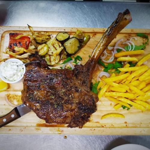 a plate of food with a piece of meat and french fries at The Wave in Sidari