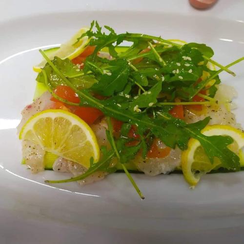 a plate of food with fish with vegetables and lemon slices at The Wave in Sidari