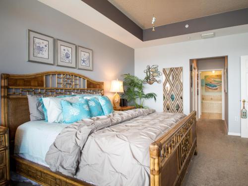 una camera da letto con un grande letto in legno con cuscini blu di Harborview Grande 803 a Clearwater Beach