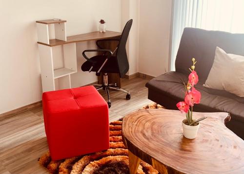 a living room with a red ottoman and a table at Apartamento zona colonial lindísimo (102) in Zipaquirá