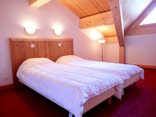 a bedroom with a large bed with white sheets at Chalet des Neiges Plein Sud in Val Thorens