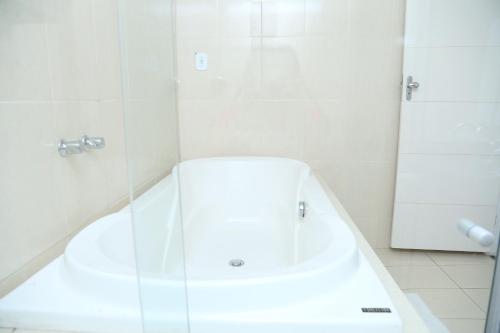 a white bathroom with a tub and a shower at Avelan Plaza Hotel in Nossa Senhora da Glória