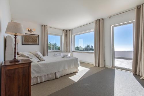 Un dormitorio con una cama y grandes ventanales. en Luxury Beachfront Villa, en Colares