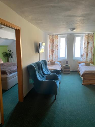 a hotel room with two beds and a blue couch at Wellness Penzion Zora Family in Tatranská Lomnica