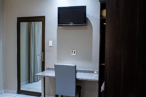 a room with a desk with a television on the wall at Machauka Lodge in Lephalale