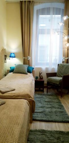 a bedroom with two beds and a window and a couch at Diána Apartmanház in Keszthely