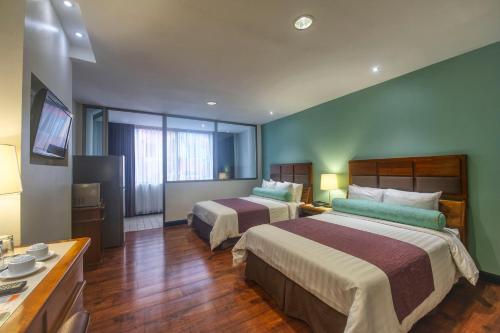 a hotel room with two beds and a television at Balmoral Hotel San José CR, Historic District in San José