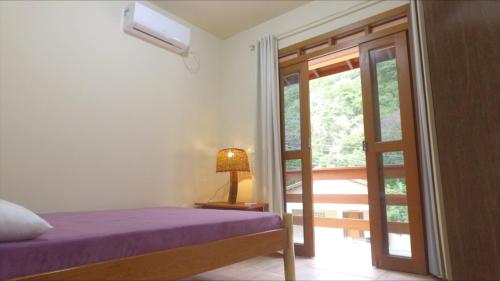 1 dormitorio con 1 cama y puerta a un balcón en Residencial do Cadinho en Pinheira