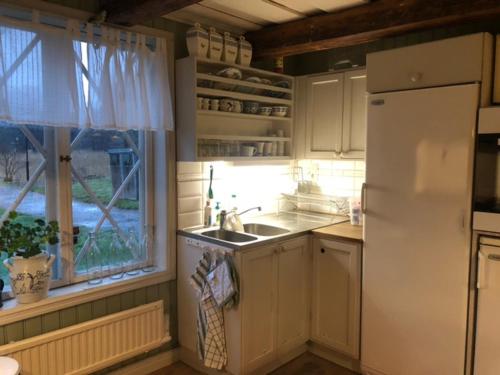 a kitchen with a sink and a refrigerator and a window at Notholmen, Tyresö in Tyresö