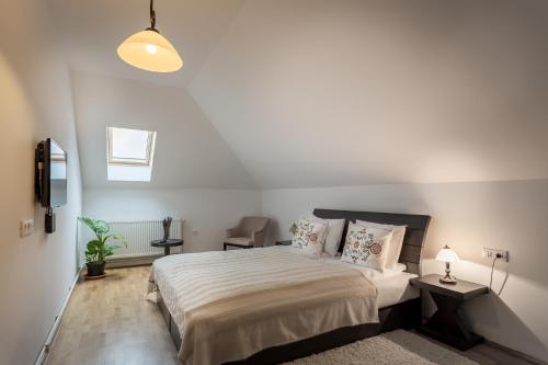 a white bedroom with a bed and a chair at Cetatuia in Măgura