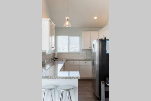 a kitchen with white cabinets and a black refrigerator at Beach Front on West Beach in Galveston