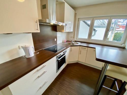 Elle comprend une petite cuisine avec des placards blancs et une fenêtre. dans l'établissement Zentrales WG-Zimmer 1 Ravensburg, Balkon, Kamin, à Ravensbourg