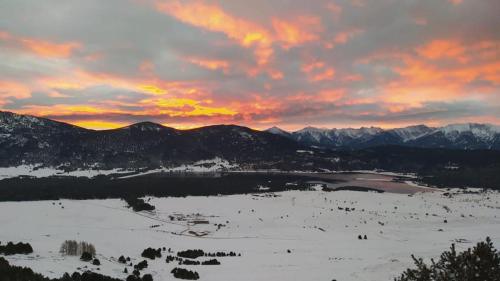 un coucher de soleil sur une chaîne de montagnes enneigée avec un lac dans l'établissement Là-Haut, aux Angles