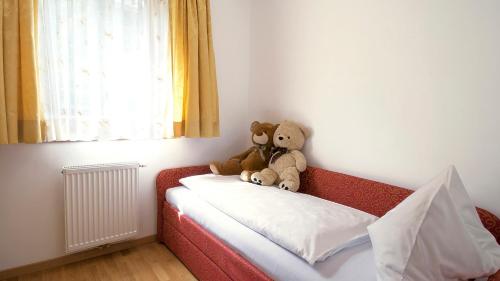 two teddy bears sitting on the back of a bed at Hotel Sonnenhof in Marlengo
