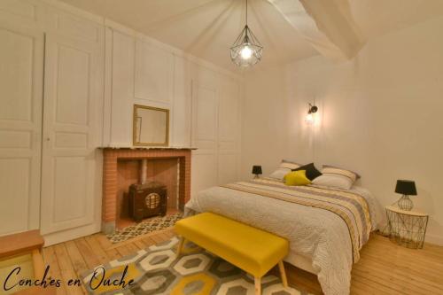 1 dormitorio con 1 cama con banco amarillo y chimenea en Hyper-centre de Conches-en-Ouche., en Conches-en-Ouche