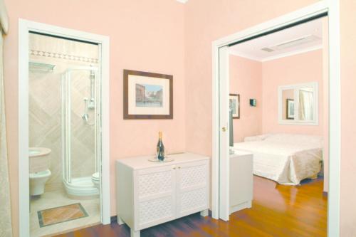 um quarto rosa com uma cama e uma casa de banho em Colosseo Studio Suite em Roma