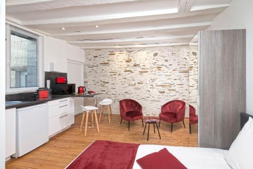 Cet appartement comprend une chambre avec des chaises rouges et une cuisine dotée d'un mur en briques. dans l'établissement Hypercentre Calme et Cosy, Impasse Saint Julien, 2eme étage, à Angers