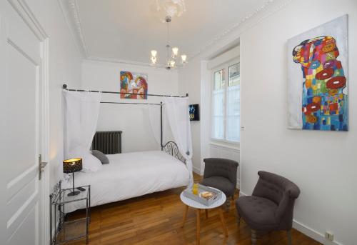 ein weißes Schlafzimmer mit einem Bett und 2 Stühlen in der Unterkunft Hyper Centre Rue Valdemaine in Angers