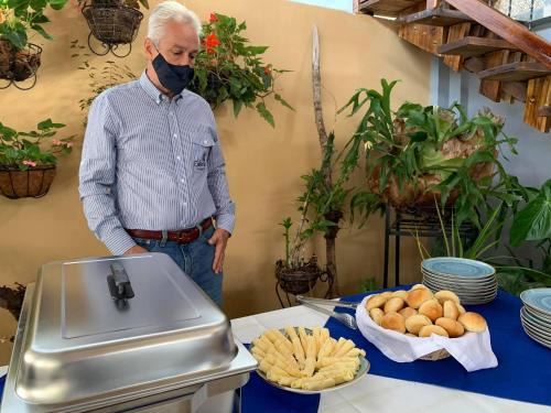 a man wearing a mask standing next to a table with food at La Estancia Hotel Boutique in Salamina