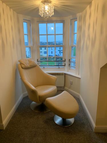 a chair and a stool in a room with windows at Ayr Loft Apartment with Fabulous Views in Ayr