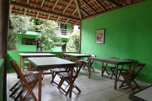 a restaurant with tables and chairs in a green wall at Pousada Jambo Trindade in Trindade