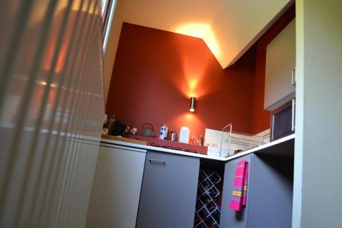 a small kitchen with orange walls and white cabinets at Villa des Roses Voltaire in Brussels