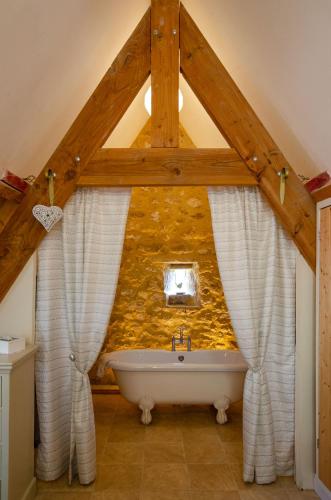 La salle de bains est pourvue d'un mur en pierre et d'une baignoire. dans l'établissement Logis de Chalons en Périgord, à Domme