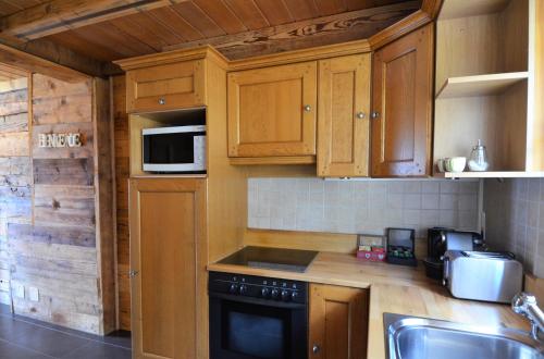 a kitchen with wooden cabinets and a stove top oven at Les chambres et Roulottes des Noisetiers in Leysin