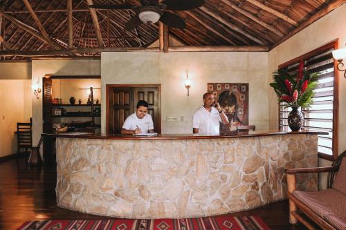 two men standing at a bar in a room at Gaia Riverlodge in San Ignacio