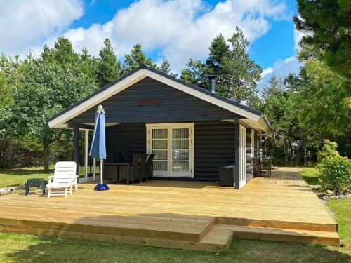 eine Hütte mit einer Terrasse, einem Stuhl und einem Sonnenschirm in der Unterkunft 4 person holiday home in Bl vand in Ho