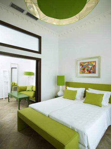 a bedroom with a large bed with a green bench at Salvator Villas & Spa Hotel in Parga