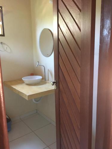 La salle de bains est pourvue d'un lavabo, d'un miroir et d'une porte. dans l'établissement Pousada Mediterraneo, à Barra Grande