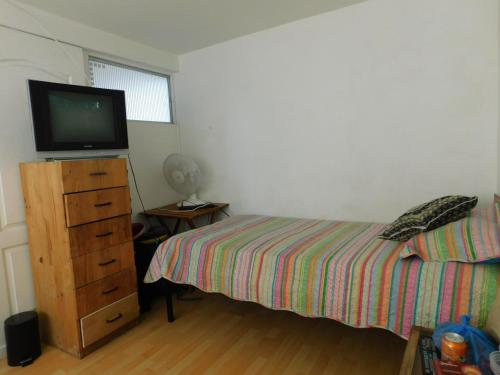 a bedroom with a bed and a television on a dresser at Hostal Pampaloja Antof in Antofagasta