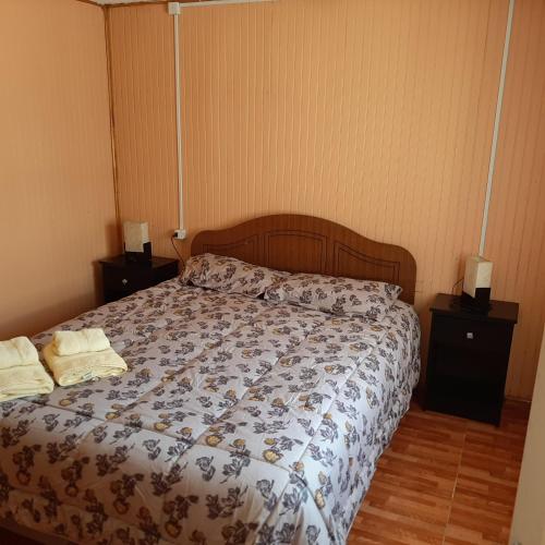 a bed in a bedroom with two night stands and two lamps at Cabaña centro Pitrufquen in Pitrufquén