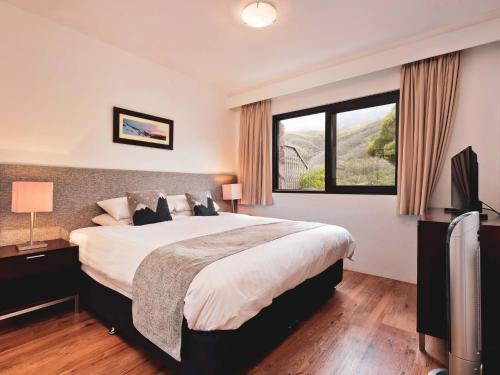 a bedroom with a large bed and a window at Lantern 1 Bedroom Deluxe with hot tub and car park in Thredbo