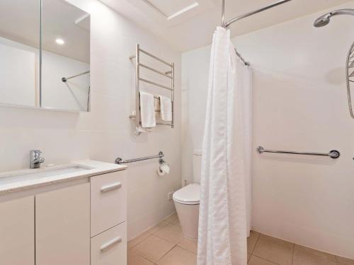 a white bathroom with a toilet and a sink at Lantern 1 Bedroom Deluxe with hot tub and car park in Thredbo