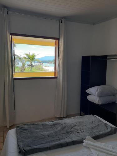 a bedroom with a bed and a window with a view of the ocean at Casa de Temporada Ceu e Mar in Praia do Bananal