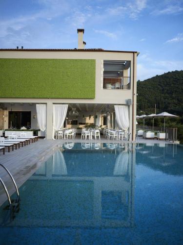 a large building with a swimming pool with tables and chairs at Salvator Villas & Spa Hotel in Parga