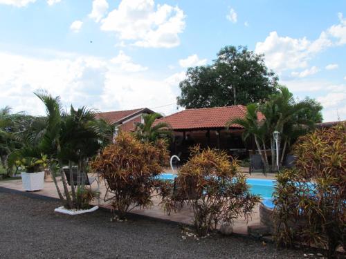 a house with a swimming pool and palm trees at Pousada Quinta Das Aroeiras in Olímpia