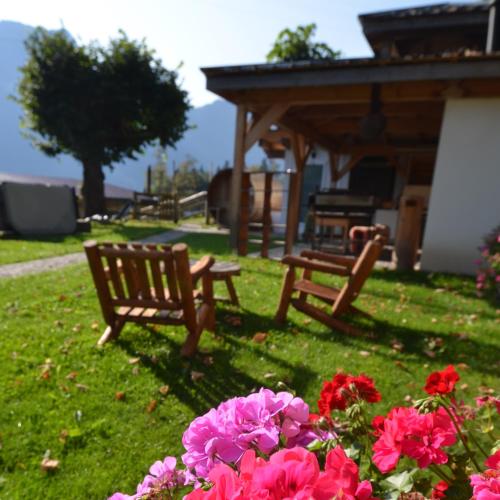 a park bench and some pink flowers in the grass at Les chambres et Roulottes des Noisetiers in Leysin