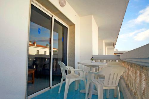 a balcony with white chairs and a table and window at Europa Family Apartments in Blanes