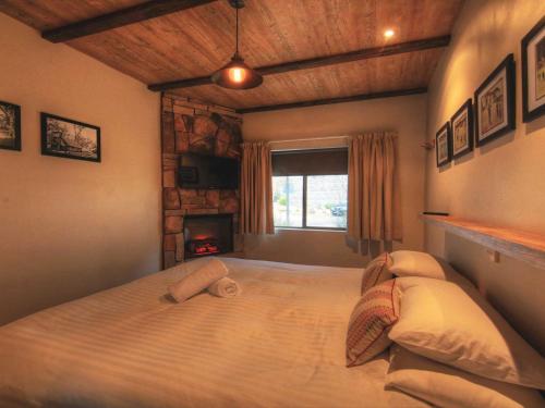 a bedroom with a large bed with a fireplace at Lantern 1 Bedroom Balcony Alpine Style in Thredbo