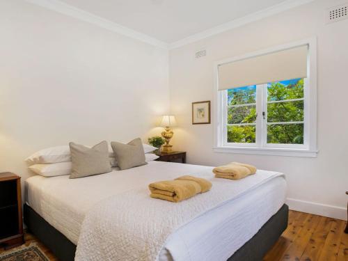 a white bedroom with a bed with two towels on it at Canary Cottage in Bowral