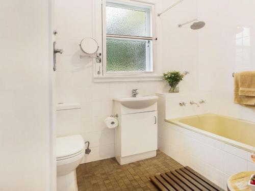La salle de bains est pourvue de toilettes, d'un lavabo et d'une baignoire. dans l'établissement Canary Cottage, à Bowral